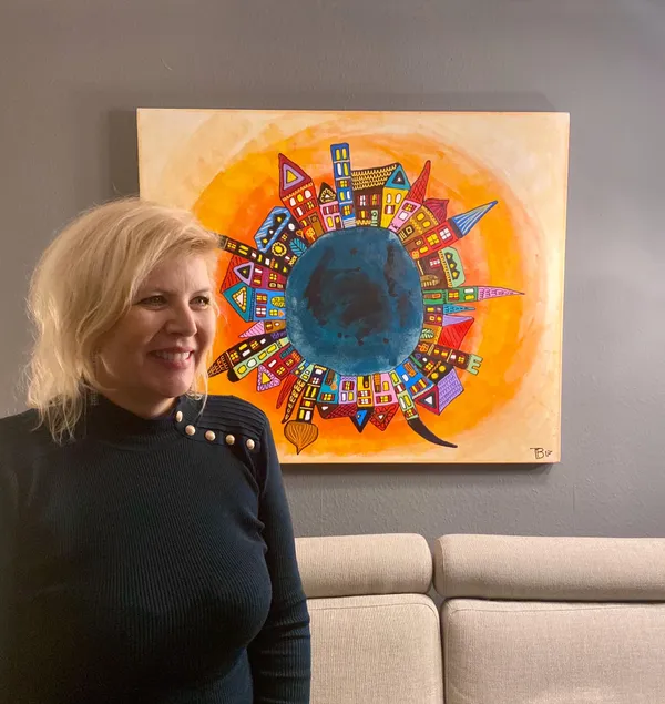 Portrait de Tatiana Bachmann devant sa peinture Ville-planète